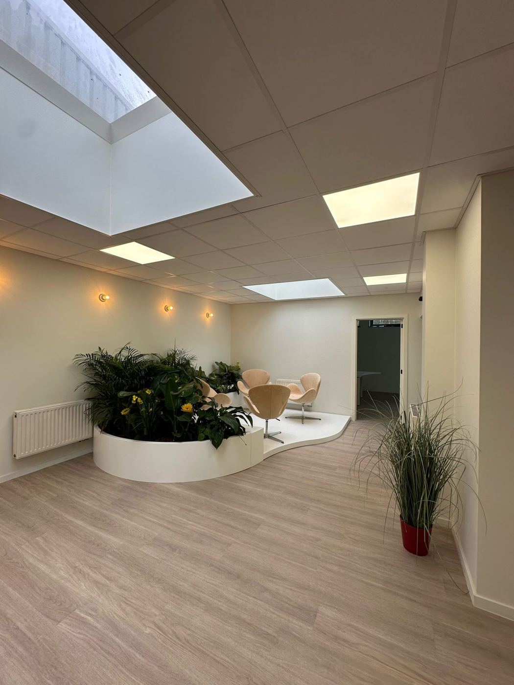 Lounge met groene plantenbak en designzetels